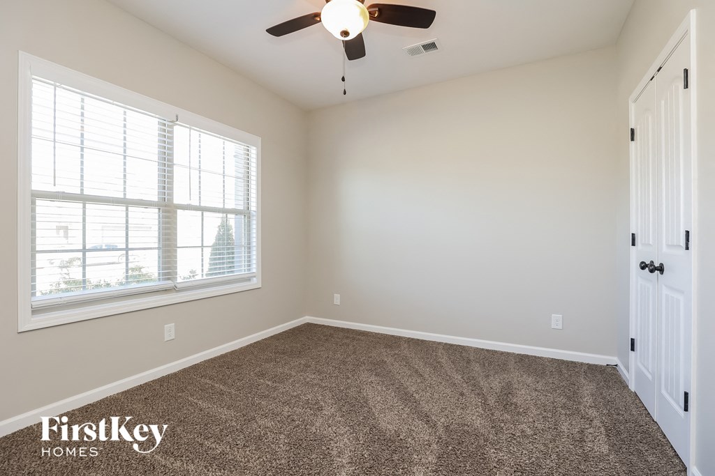 an empty room with carpet and a ceiling fan