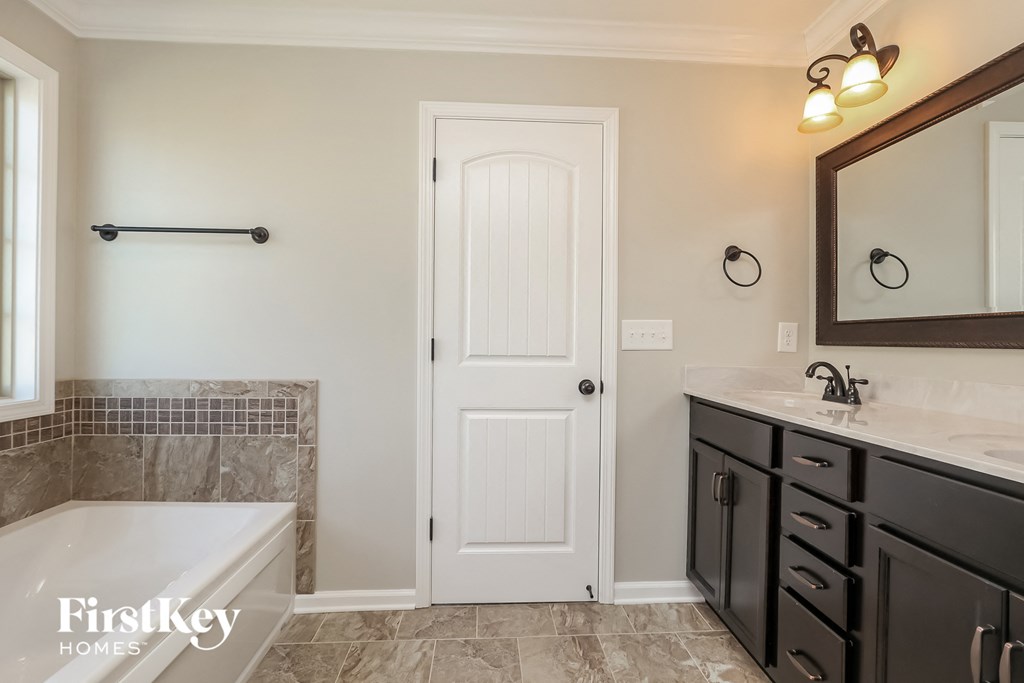 a bathroom with a tub and a sink and a white door