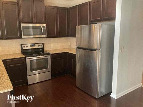 A kitchen with a stove top oven, microwave, and refrigerator.
