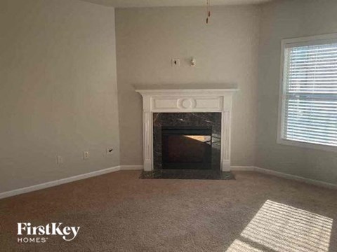 A living room with a fireplace and a carpet.