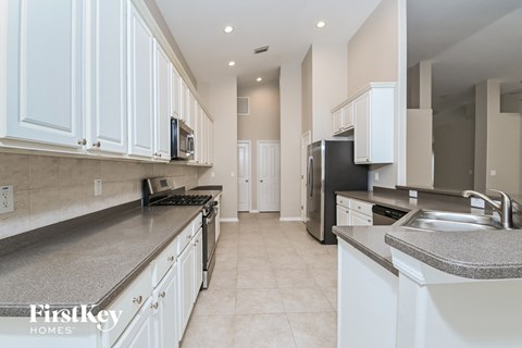 A kitchen with white cabinets and a grey counter top.