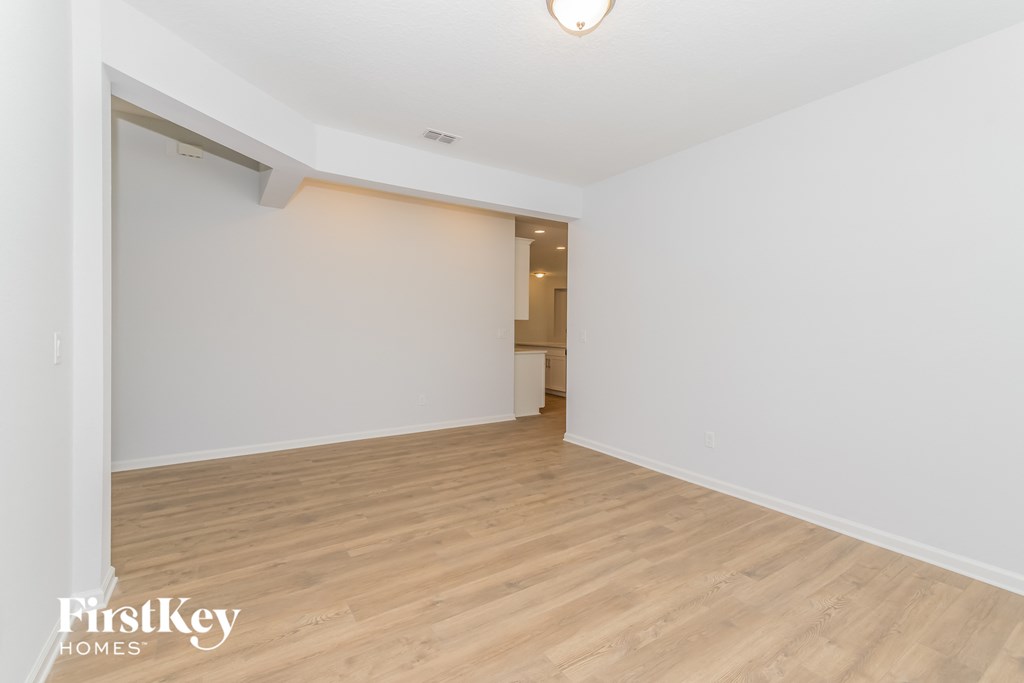 A spacious room with wooden flooring and a white wall.
