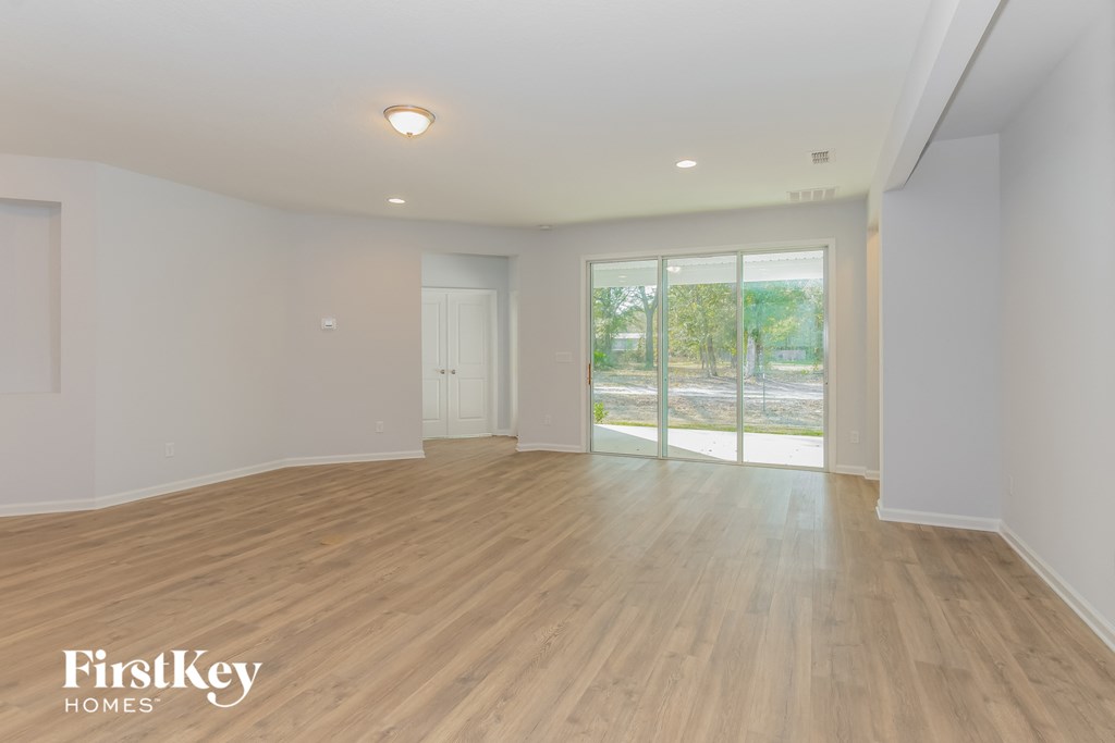 A spacious room with wooden flooring and a sliding glass door leading to a balcony.
