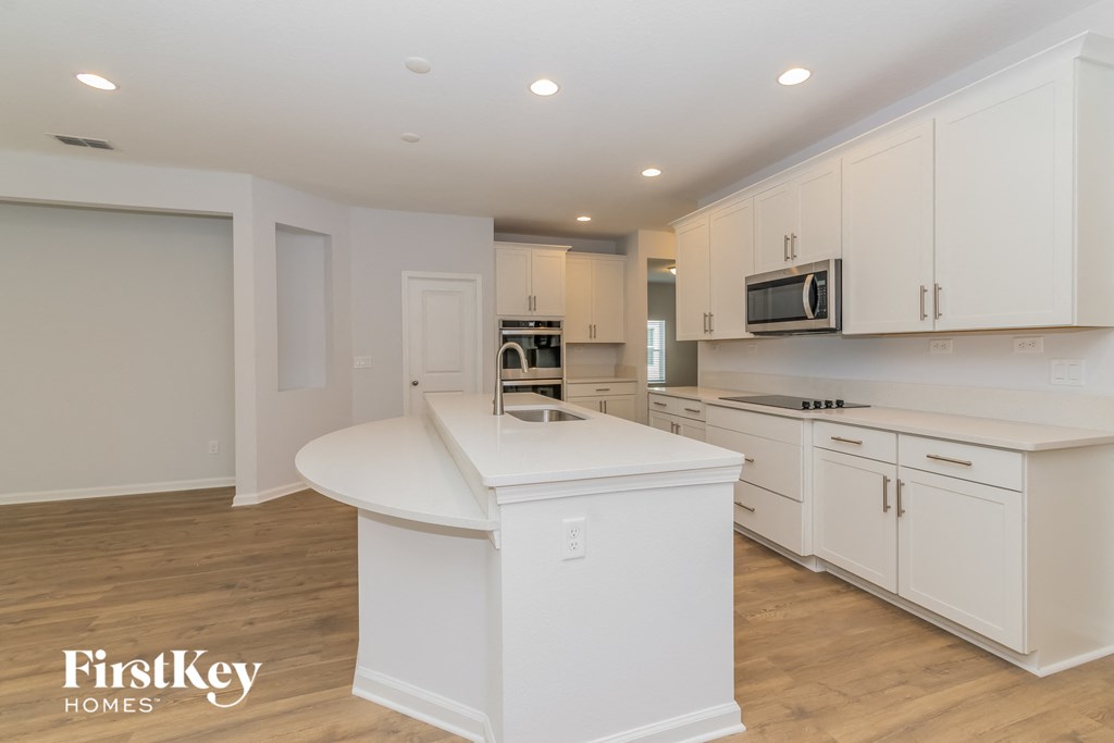 A kitchen with white cabinets and a white island.
