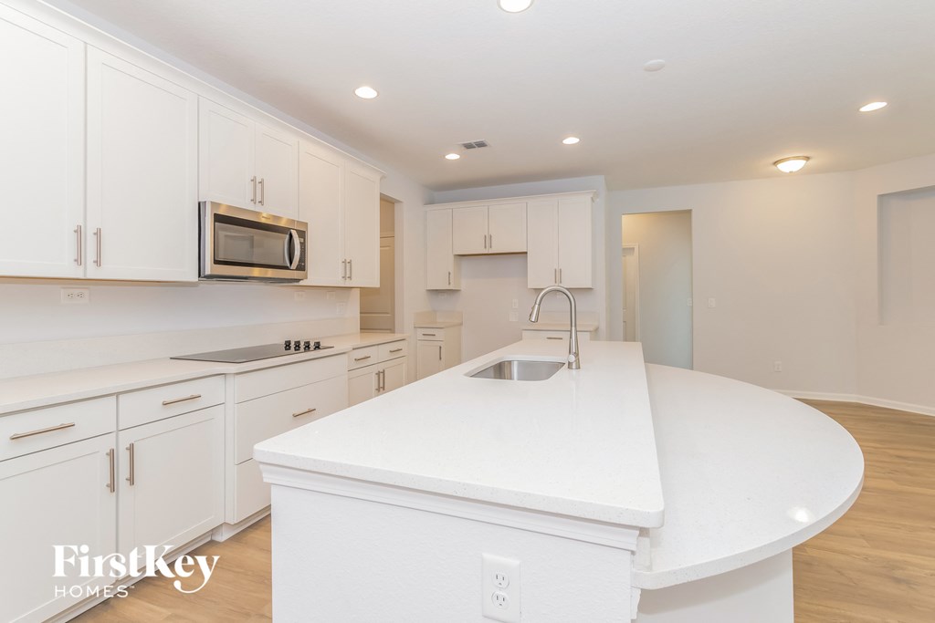 A kitchen with white cabinets and a white island.