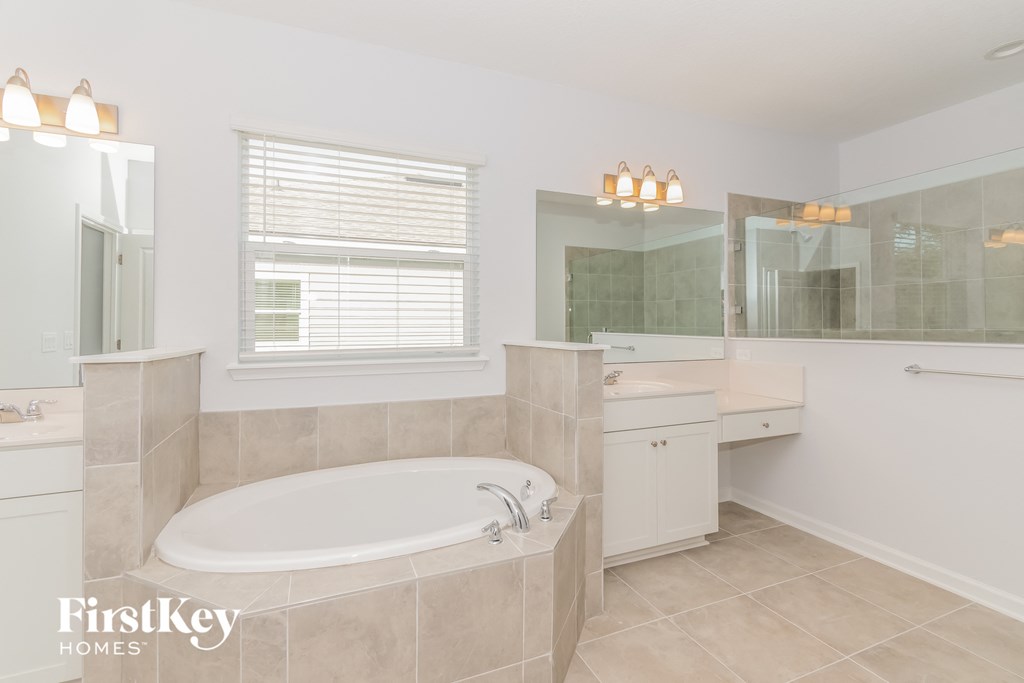 A bathroom with a tub, sink, and mirror.