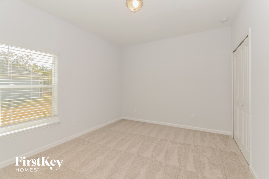 A room with a carpeted floor and a window with blinds.