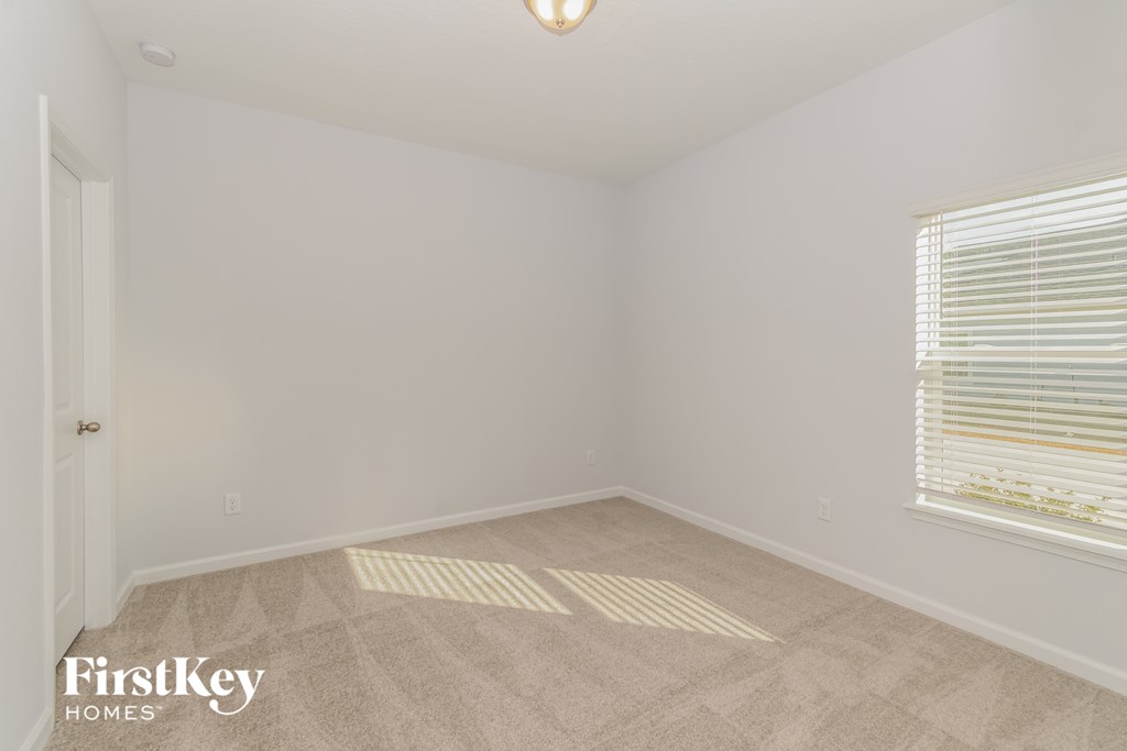 A room with a carpeted floor and a window with blinds.