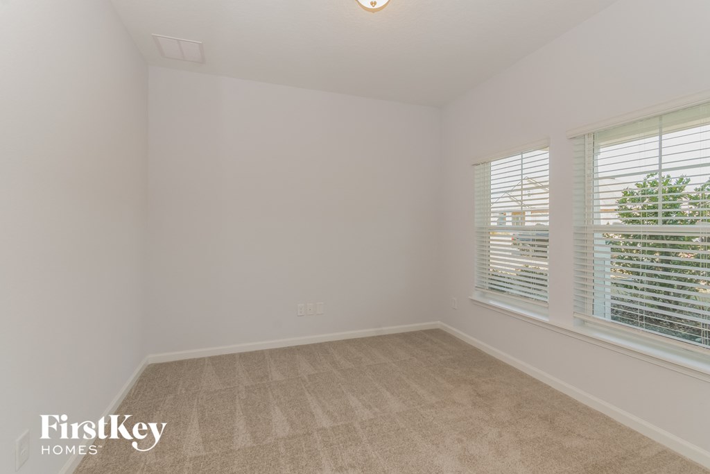 A room with a carpet floor and a window with blinds.