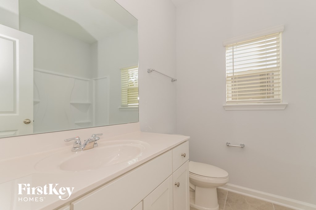 A white bathroom with a sink, toilet and mirror.