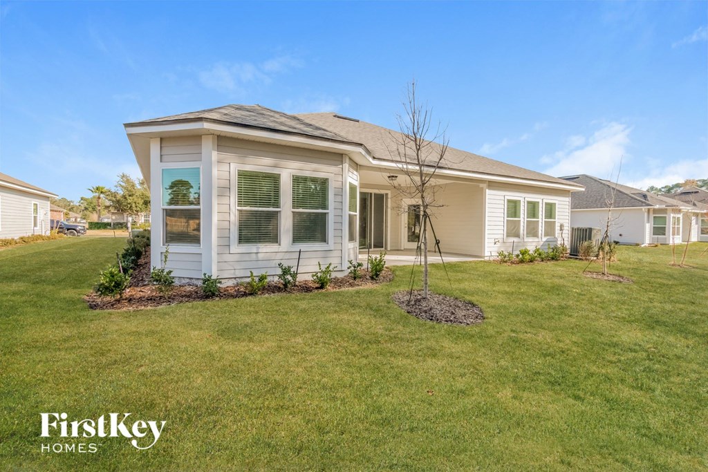 A house with a lawn and a tree in front of it.