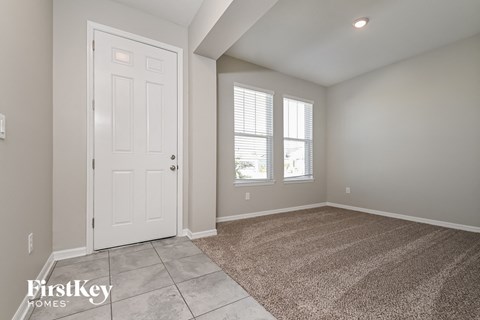 the living room of a new home with a white door and carpet