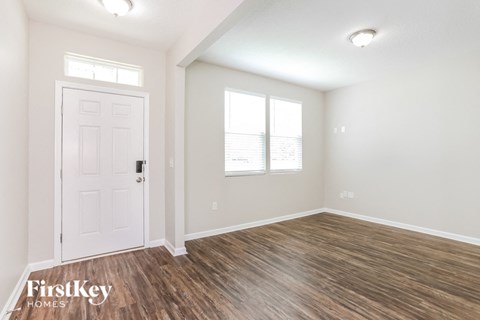 A room with a white door and wooden flooring.