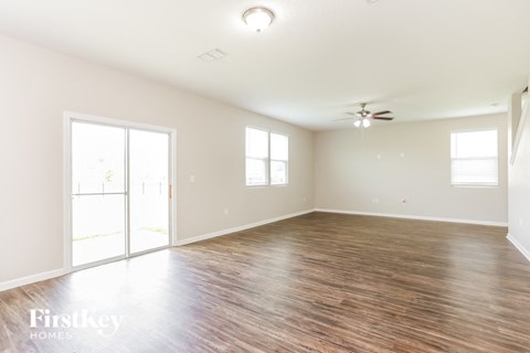 A spacious room with wooden flooring and a ceiling fan.