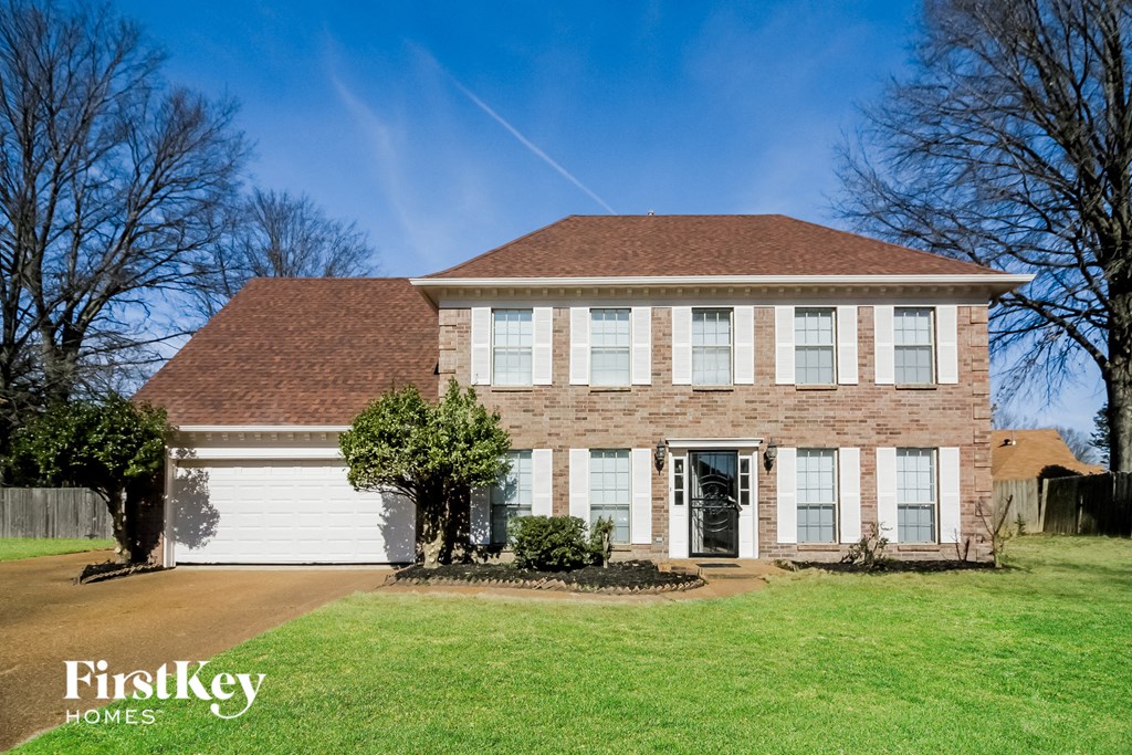 A brick house with a brown roof and a white garage door.