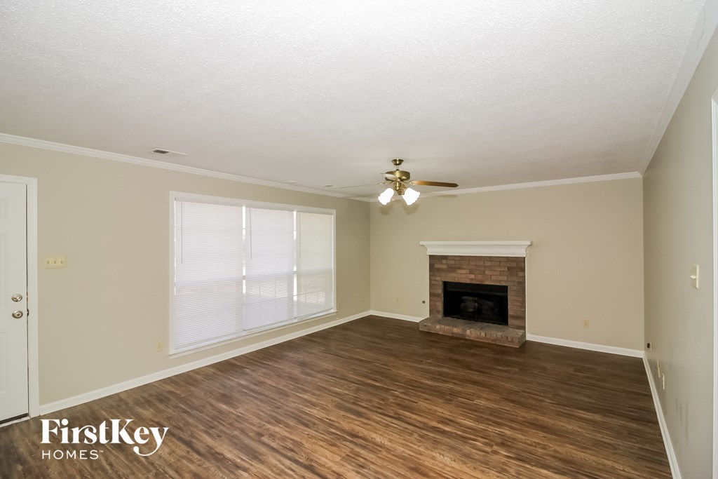 A spacious room with a fireplace and wooden floors.