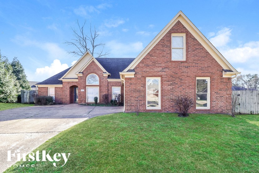 a brick house with a lawn and a driveway