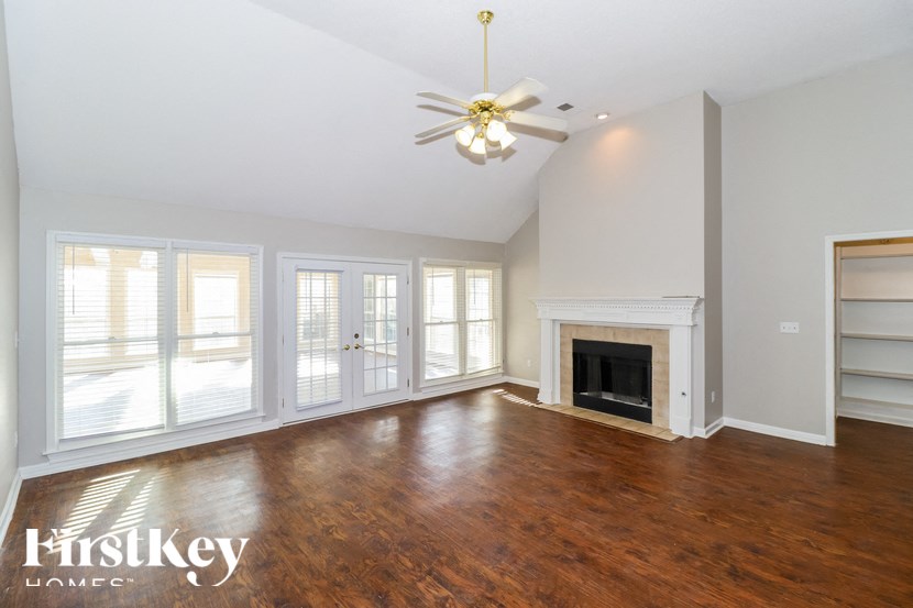 an empty living room with a fireplace and a ceiling fan