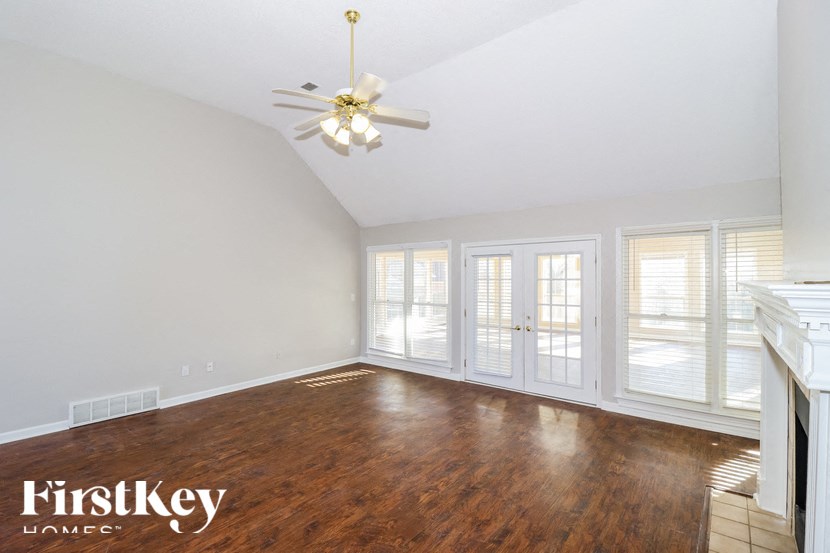 an empty living room with wood floors and a ceiling fan