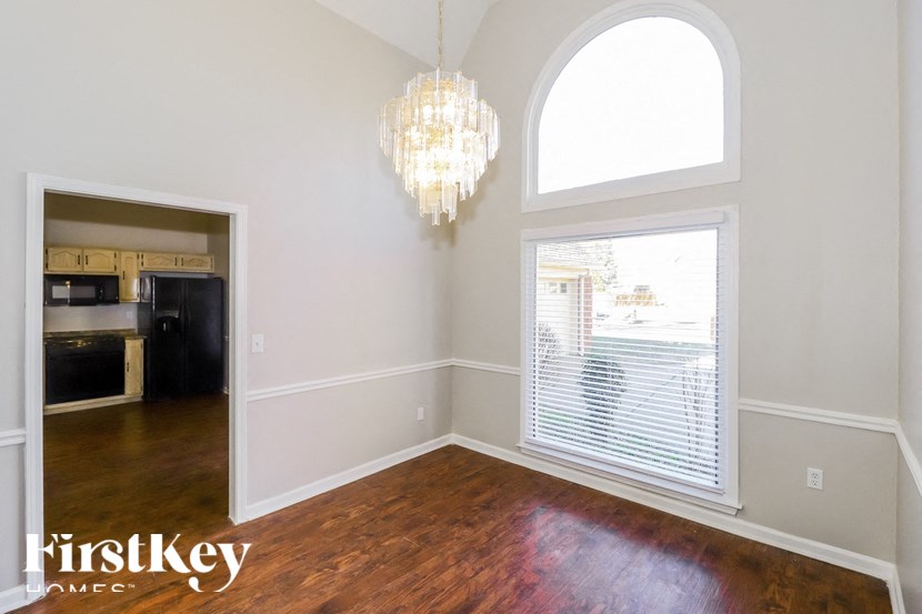 an empty living room with a large window and a chandelier