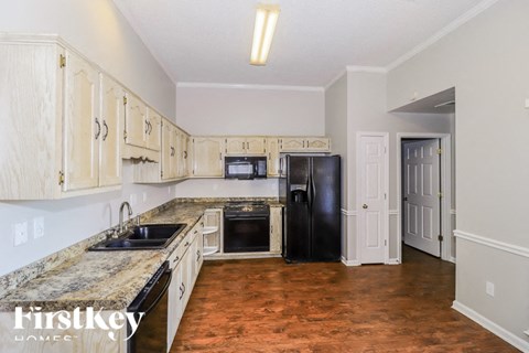 a kitchen with white cabinets and a black refrigerator