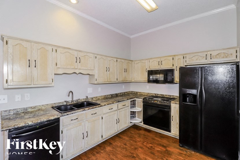a kitchen with white cabinets and black appliances