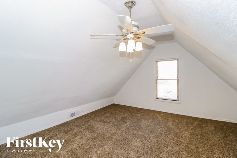 the attic of a home with a ceiling fan and carpet