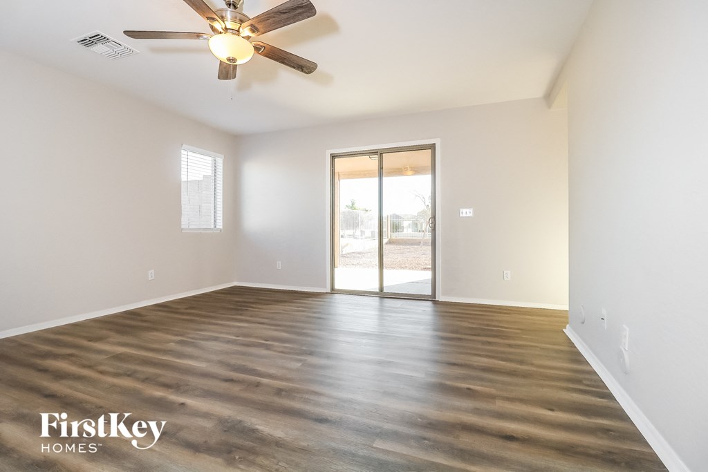 the spacious living room with wood flooring and a ceiling fan