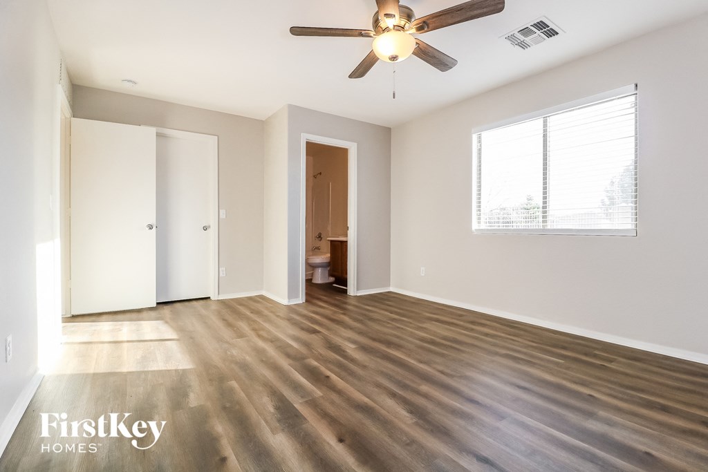 an empty living room with wood flooring and a ceiling fan