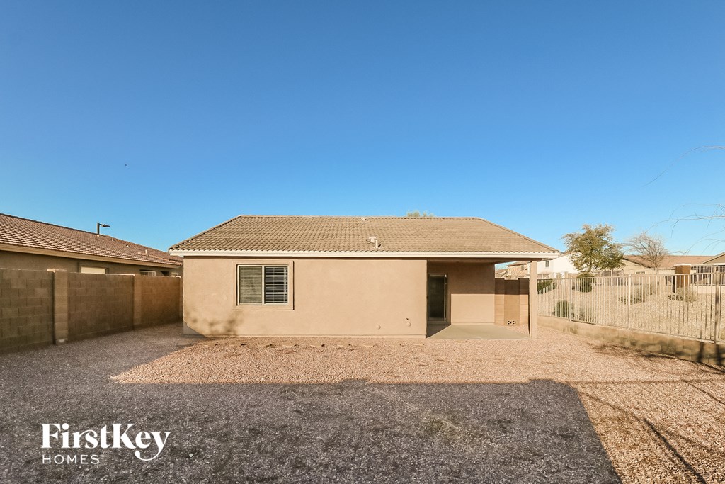 a small tan house with a driveway and a fence
