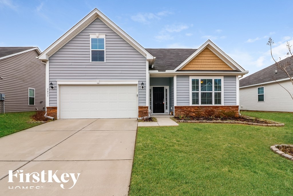 A house with a garage and a driveway in front of it.