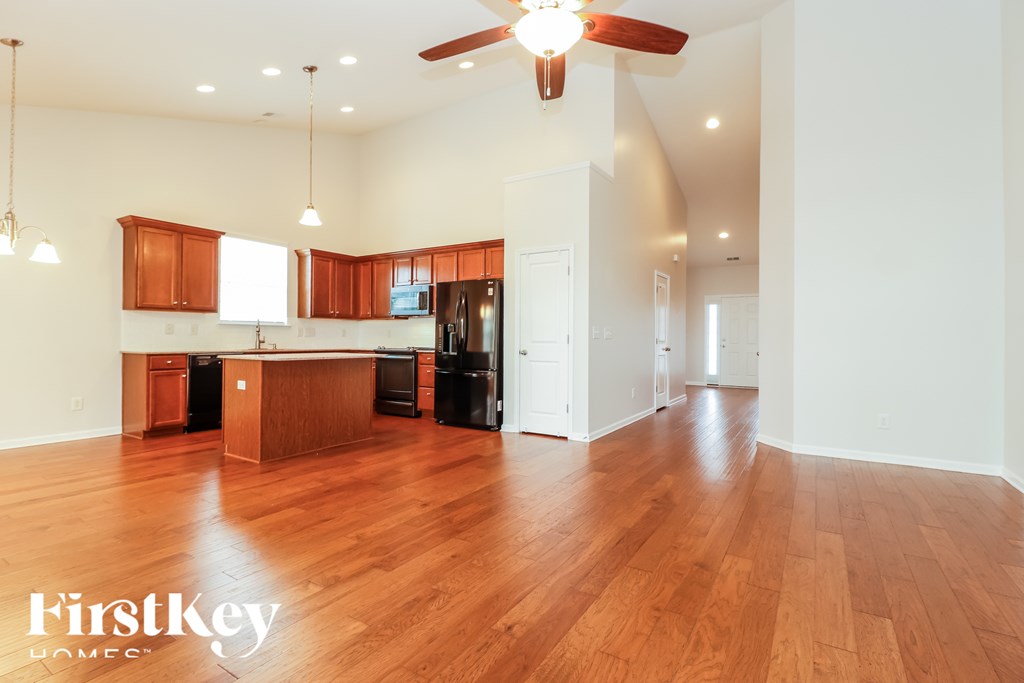 A spacious kitchen with wooden floors and a ceiling fan.