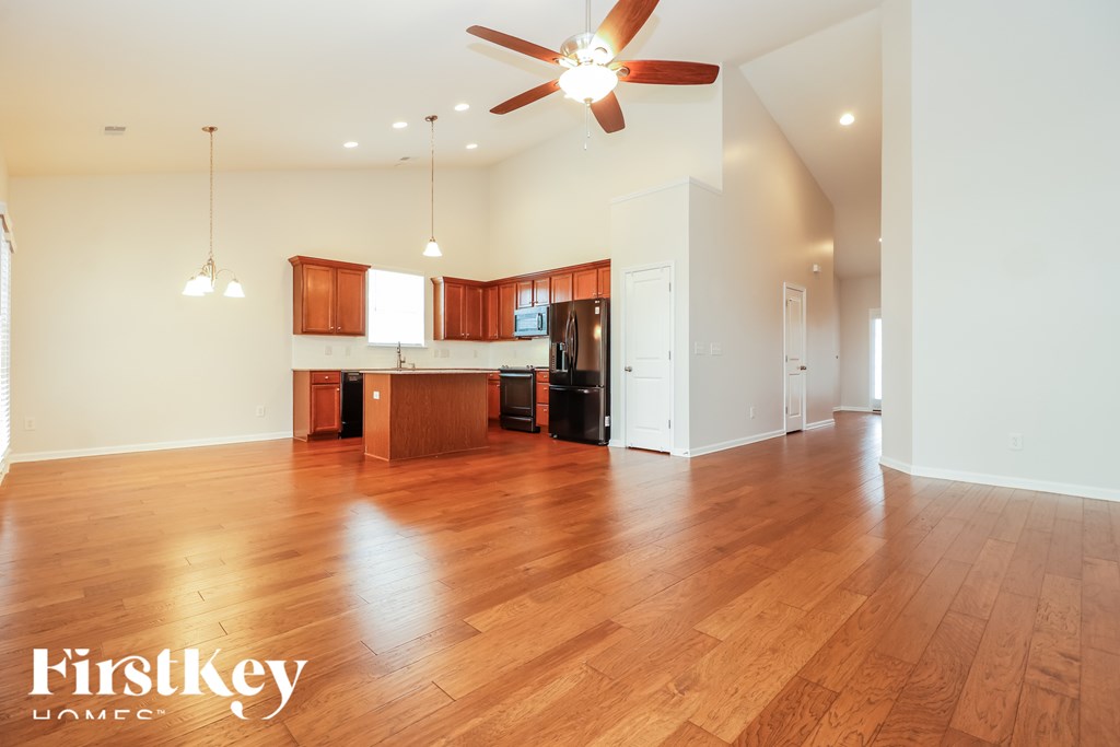 A spacious room with wooden floors and a ceiling fan.