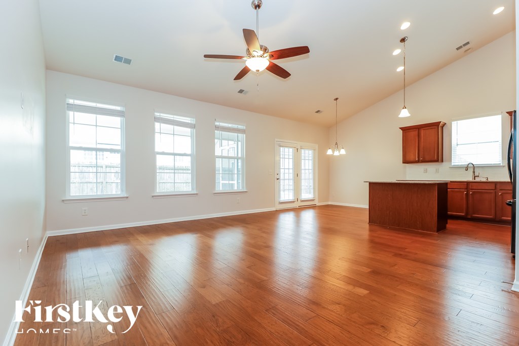 A spacious room with wooden floors and a ceiling fan.