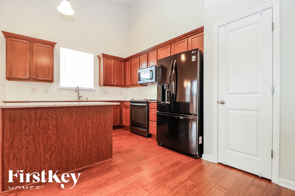 A kitchen with wooden cabinets and a black fridge.