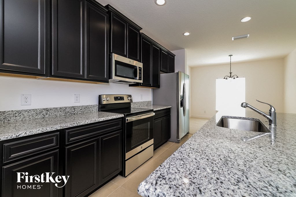 A kitchen with black cabinets and granite countertops.