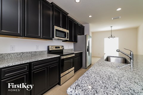 A kitchen with black cabinets and granite countertops.