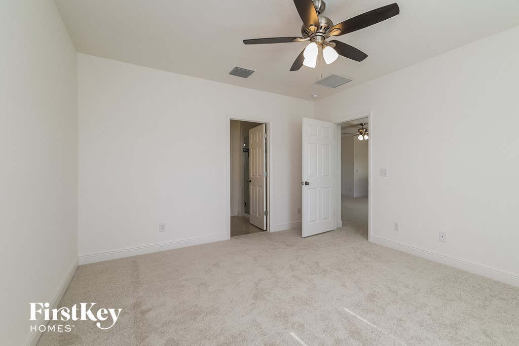 A spacious room with a ceiling fan and two doors.