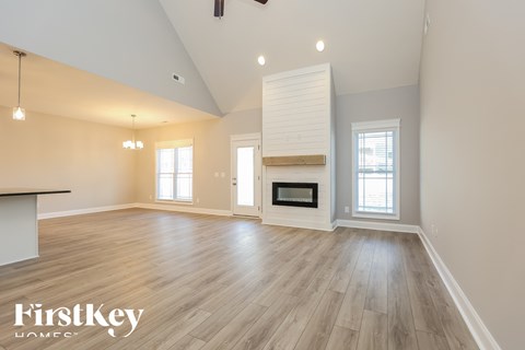 A spacious room with wooden floors and a fireplace is shown.