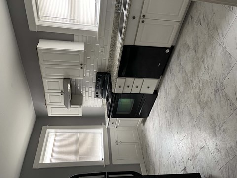 A kitchen with a black oven and white cabinets.