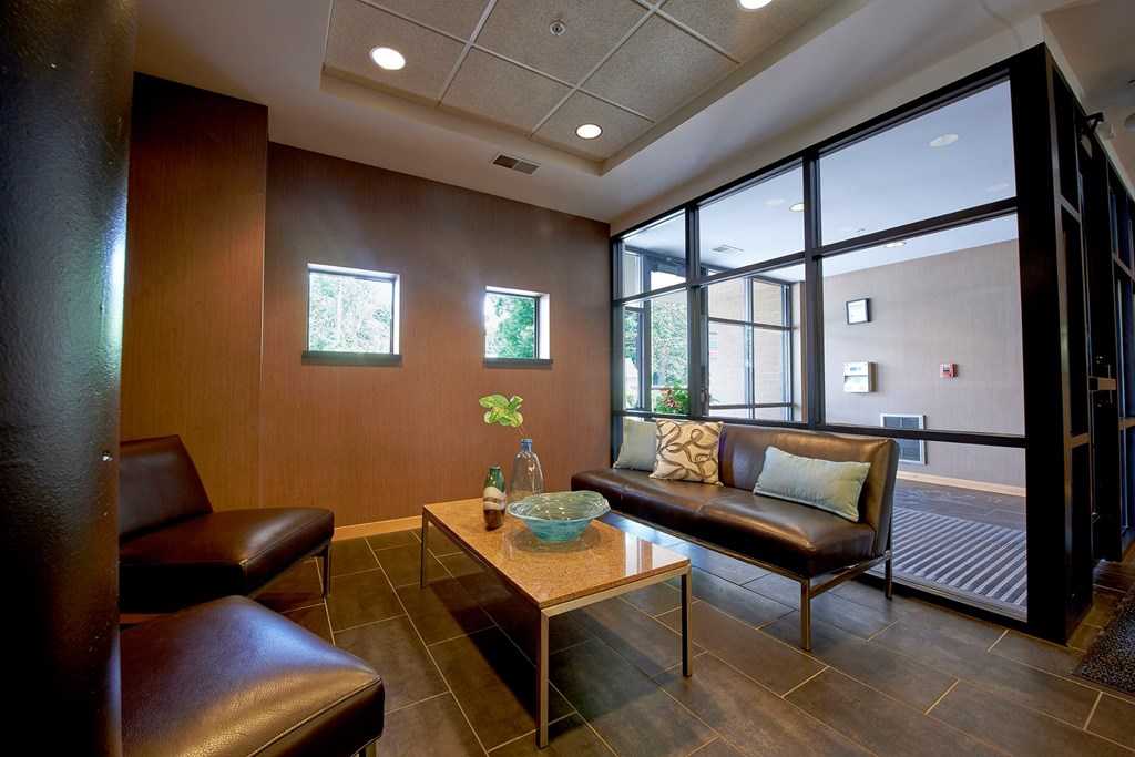 A seating area with a brown leather couch, brown leather chairs, and a coffee table.