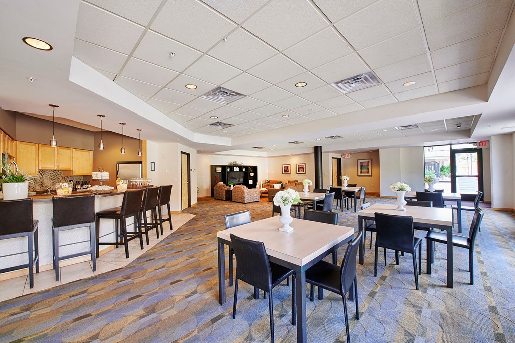 A dining area with a bar, tables and chairs.