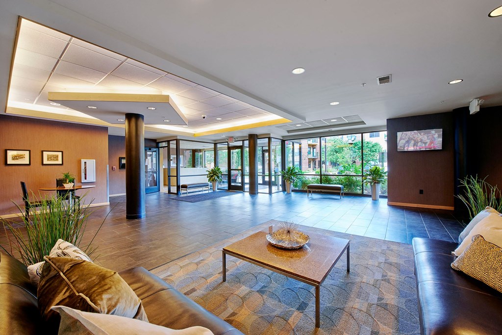 A lobby with a brown leather couch, coffee table, and benches.