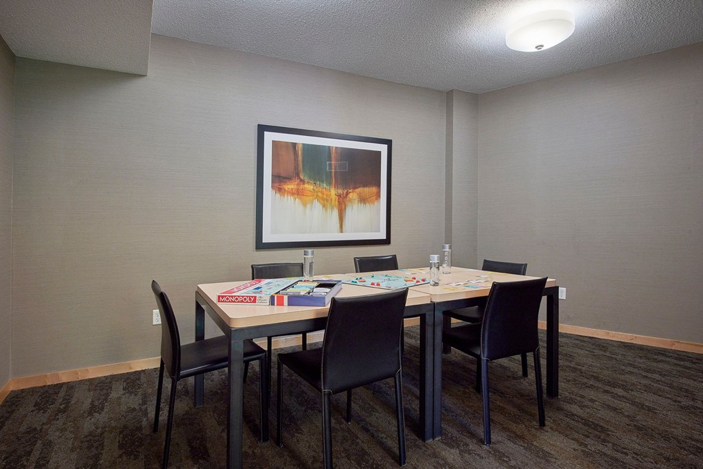 A conference room with a table, chairs, and a painting on the wall.