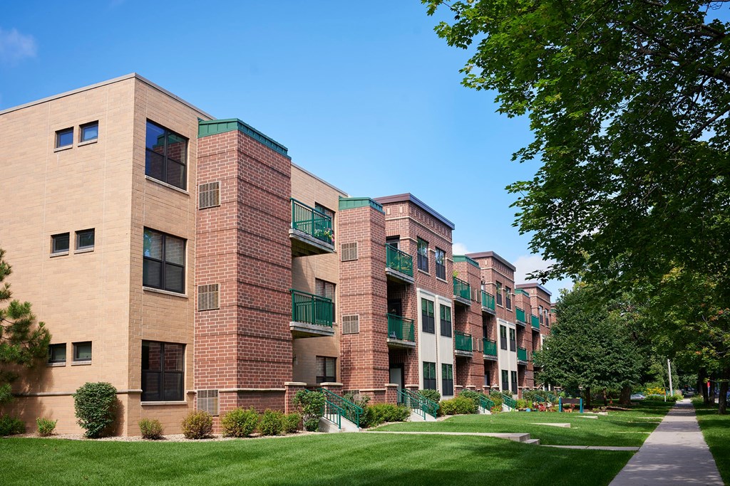 A large apartment building with balconies and a green lawn in front.