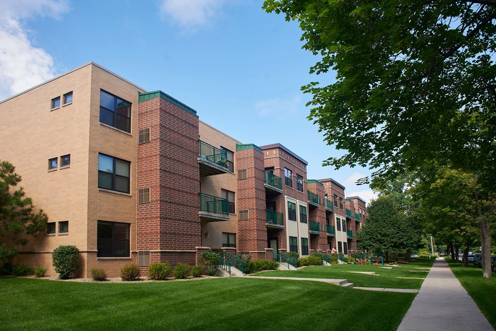 A large apartment building with balconies and a green lawn in front.
