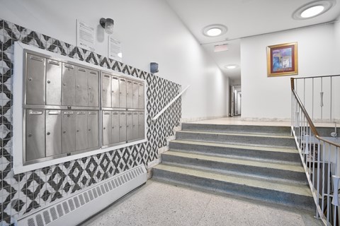 A staircase with a metal railing and a wall with a black and white patterned tile.