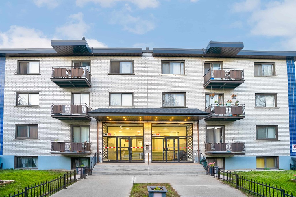 A modern apartment building with a black fence in front.