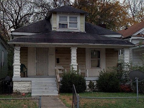 A small house with a front porch and a satellite dish on the roof.