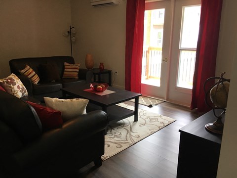 A black couch with red pillows sits in a living room.
